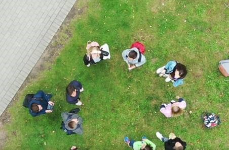 Eine Gruppe Jugendlicher lässt eine Drohne steigen; Perspektive aus der Luft