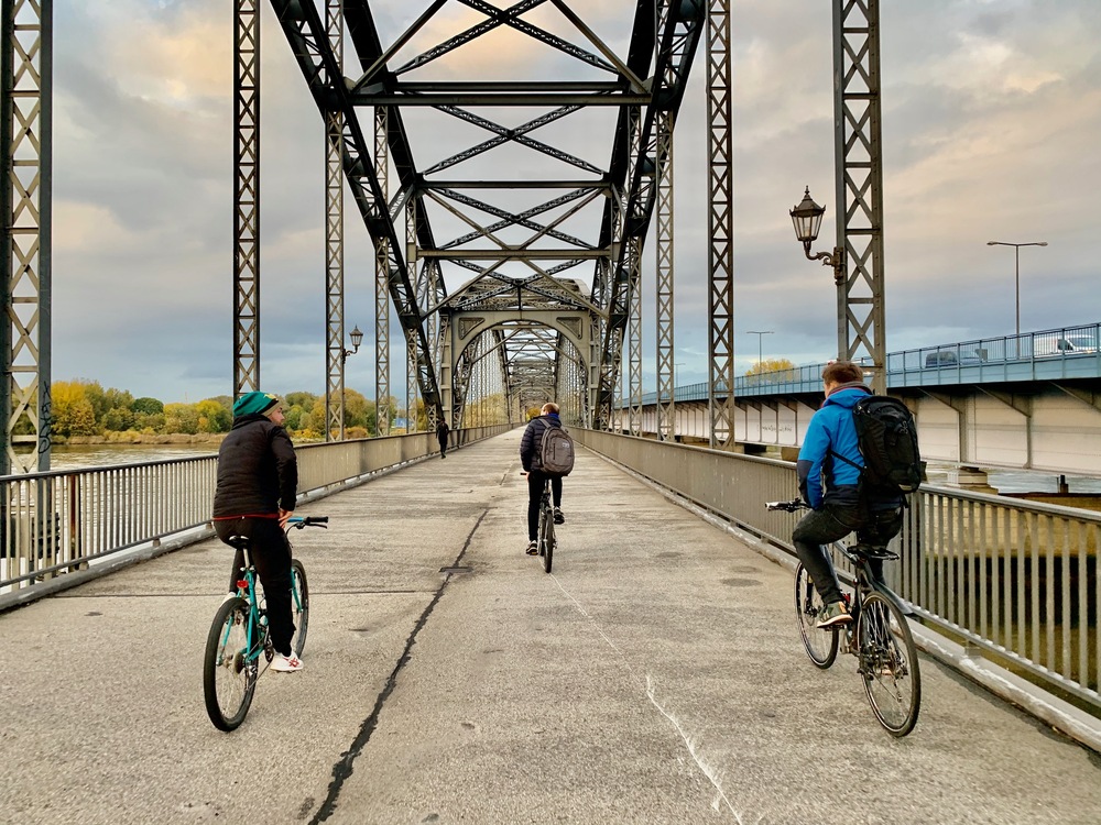 3 Menschen radeln über eine Brücke