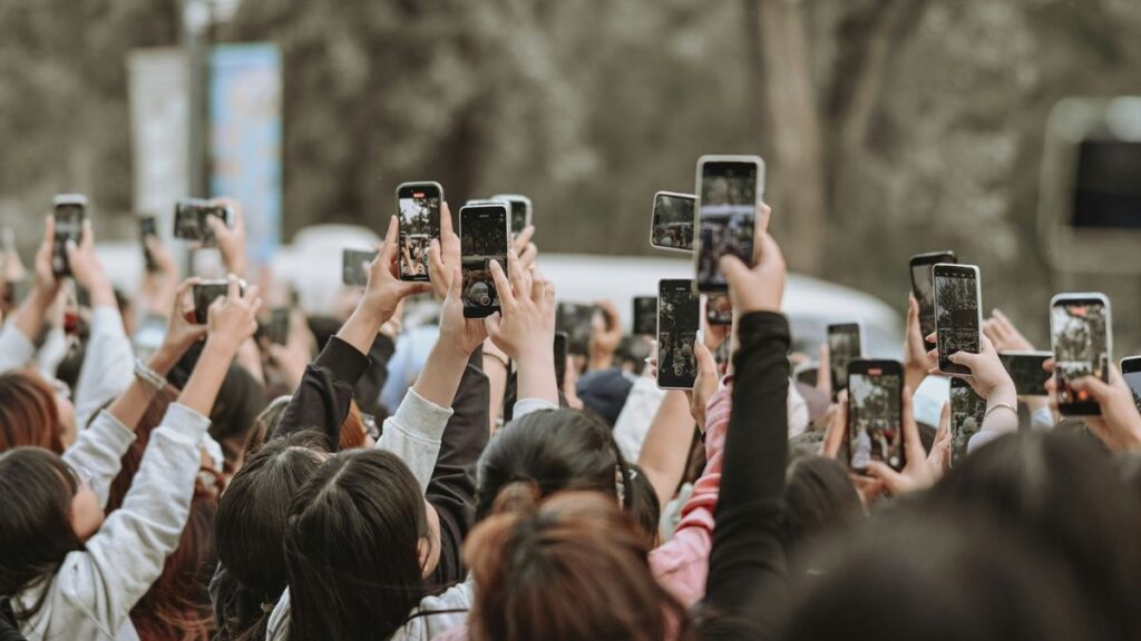 Das Bild zeigt viele Menschen, die mit einem Smartphone etwas filmen.