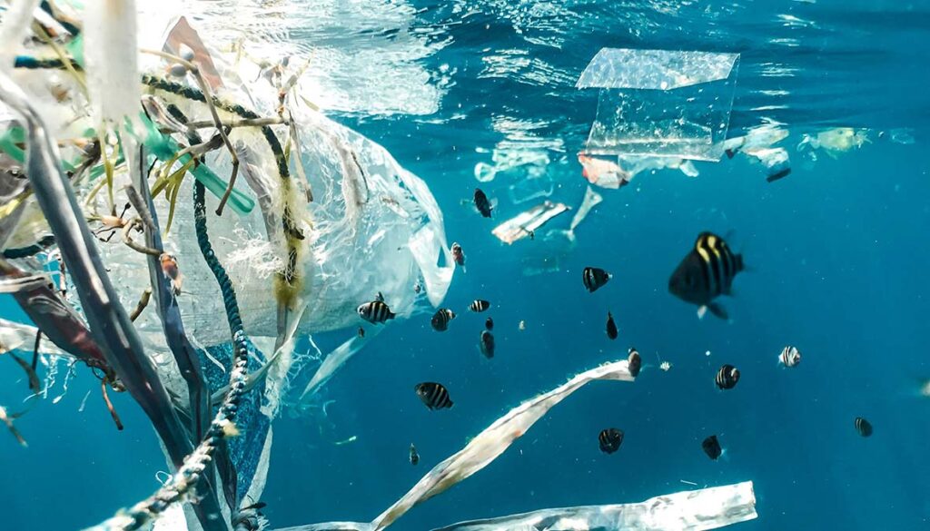 Zu sehen ist das Meer mit Plastikmüll wie Plastiktüten. Tische schwimmen umher.