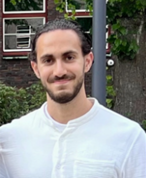 Portrait von Kasim, er hat einen Bart, braune Haare und trägt ein weißes Hemd.