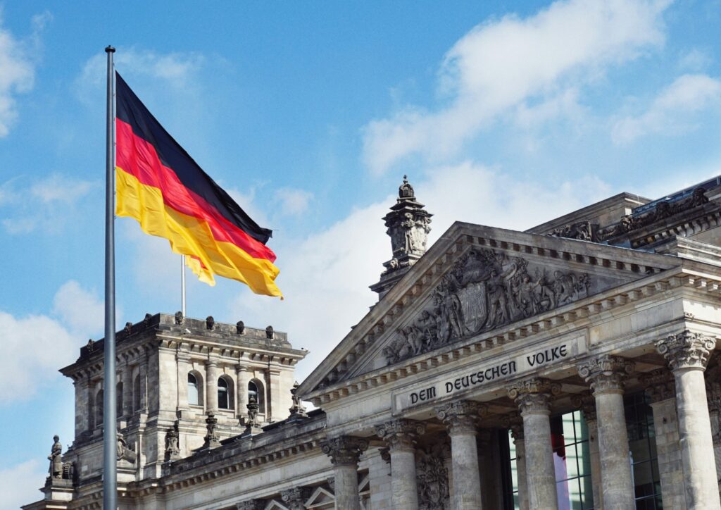 Das Bild zeigt die deutsche Flagge, die vor dem Reichstagsgebäude in Berlin weht, in dem der Bundestag tagt.
