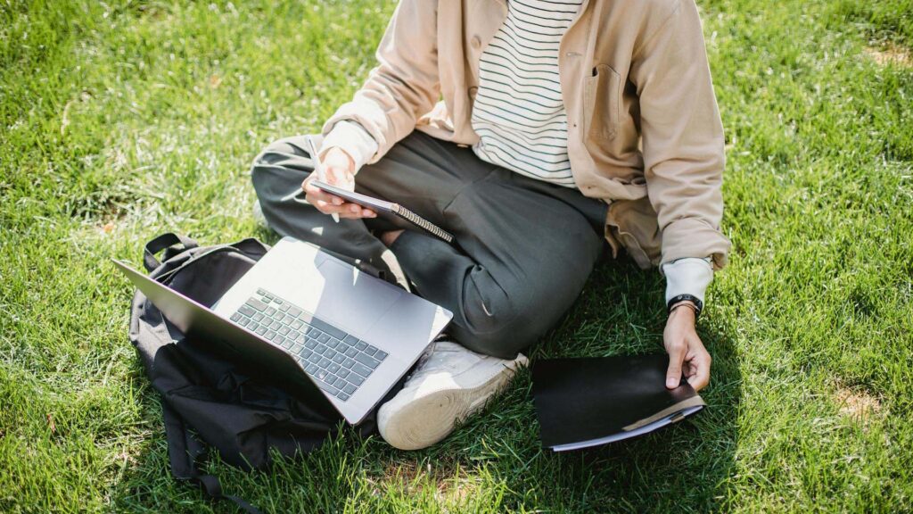 Junger Student Mit Laptop Und Notizbüchern, Die Im Park Studieren