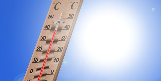 Das Bild zeigt ein Thermometer, das bis zu 40 Grad anzeigt. Dahinter ist die strahlende Sonne auf blauem Himmel zu sehen.